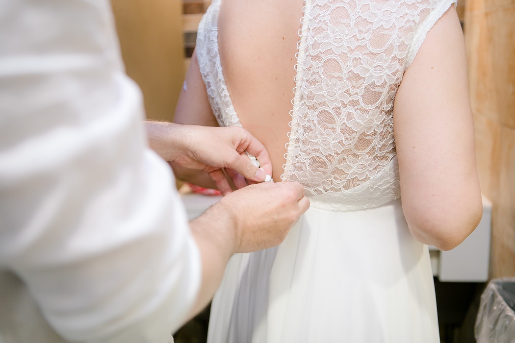 brides fiance helps her get dressed