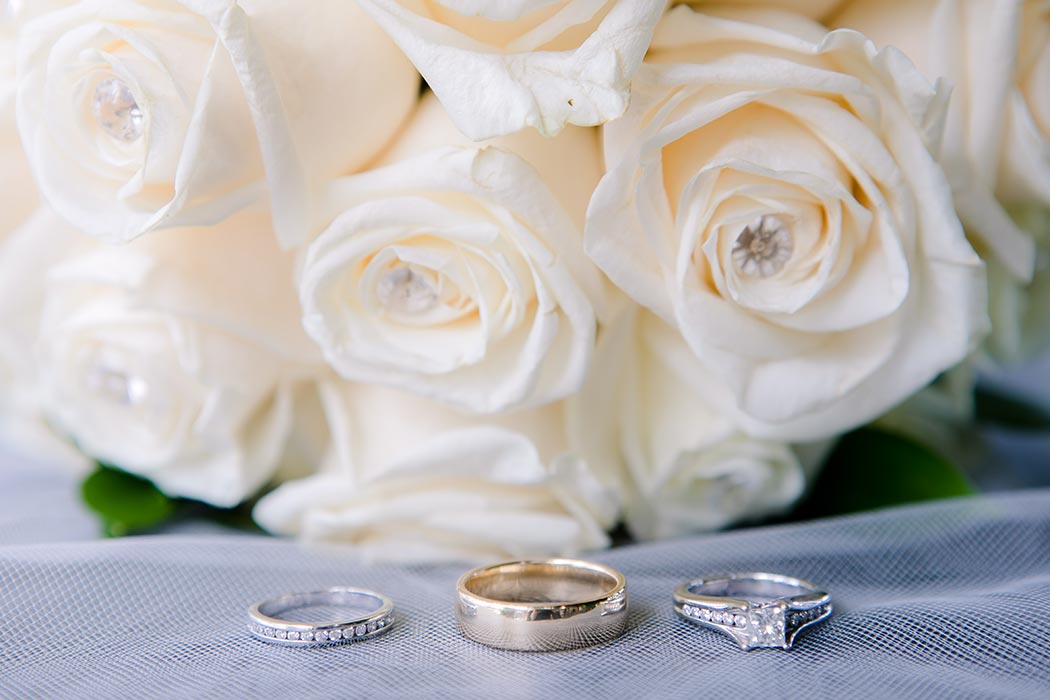 wedding photography details with wedding rings and white rose bouquet