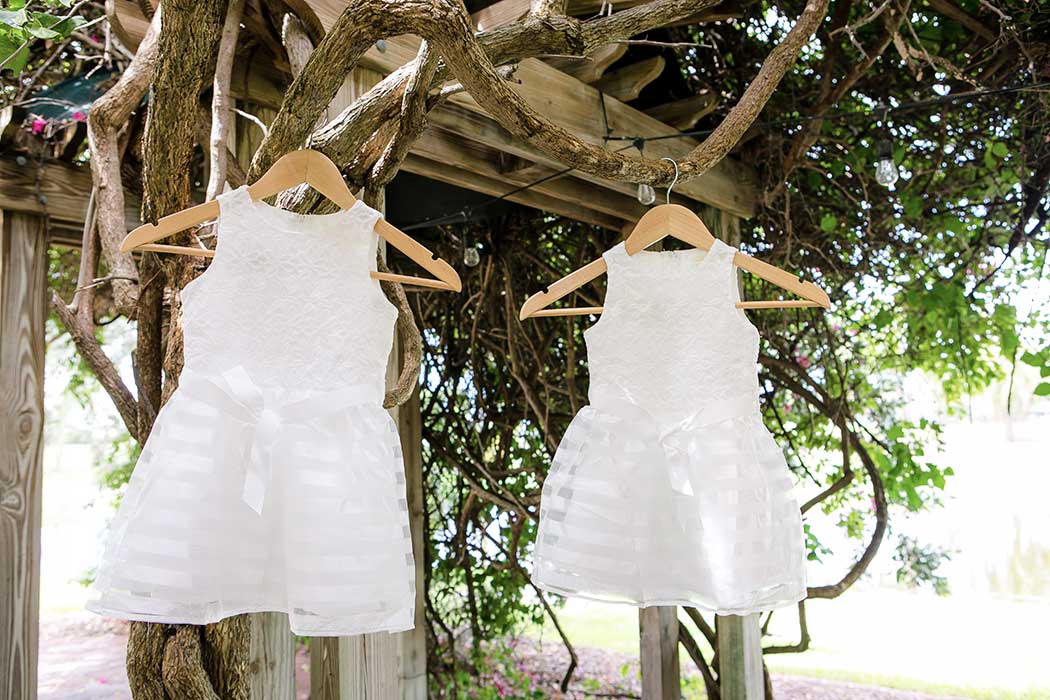 adorable white flower girl dresses hanging from trellis