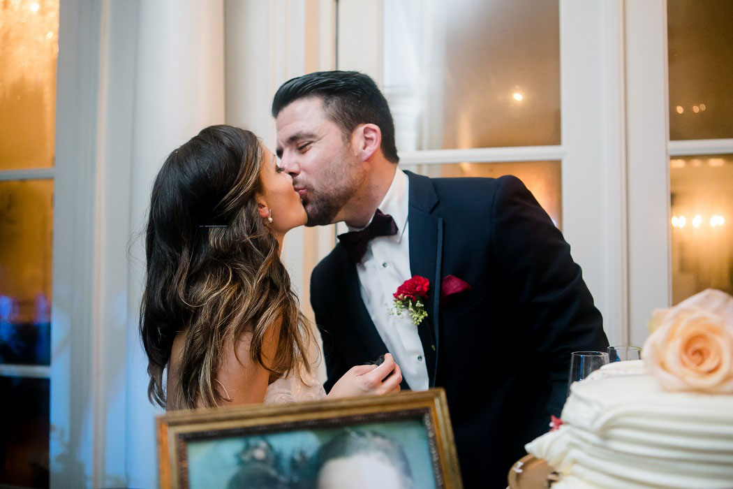 bride and groom kiss after cutting their wedding cake