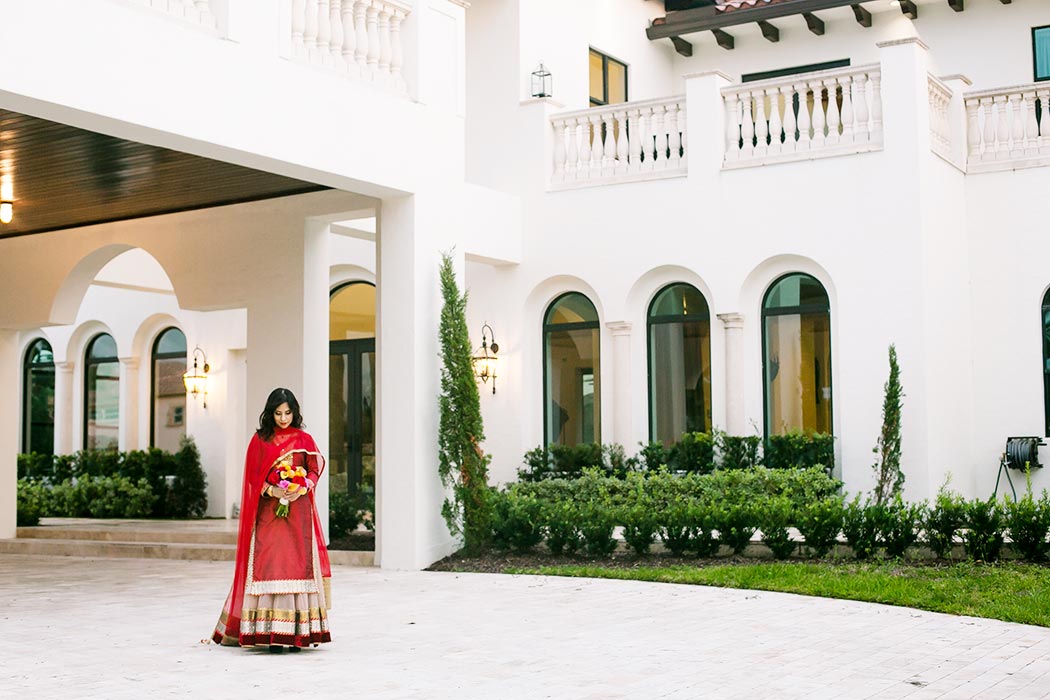 bride poses wearing red and gold sari at an indian wedding styled photoshoot