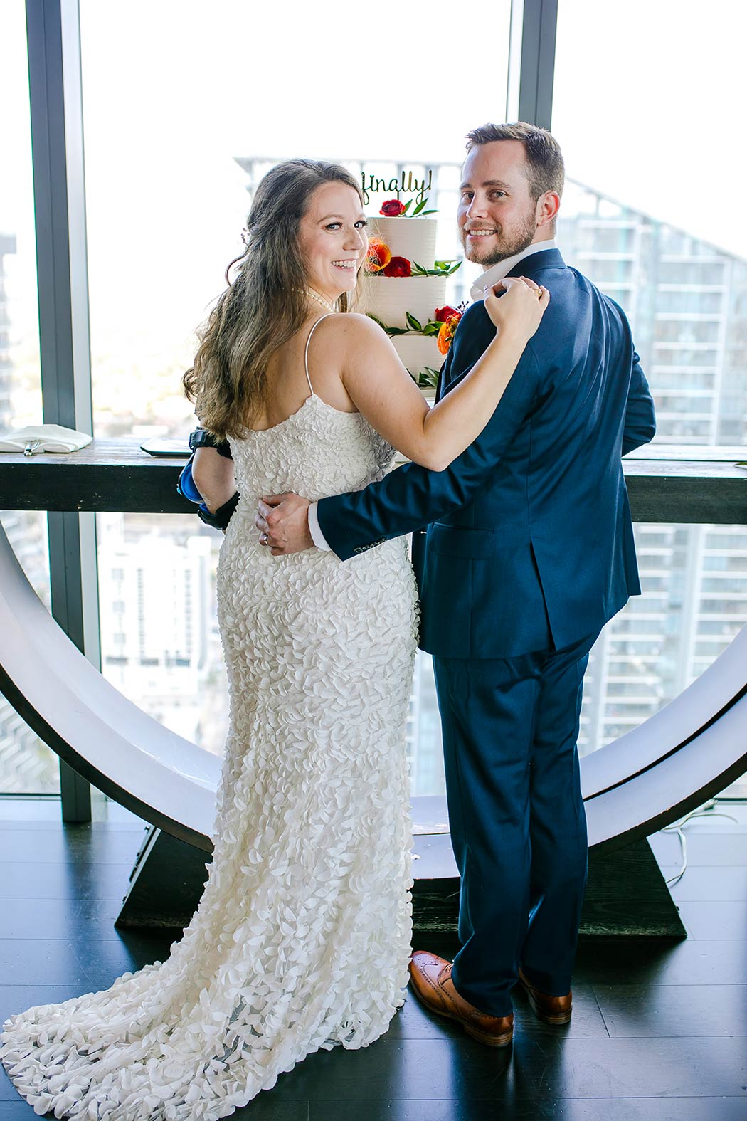 bride and groom pose in front of modern wedding cake with funny wedding cake topper | east hotel miami wedding