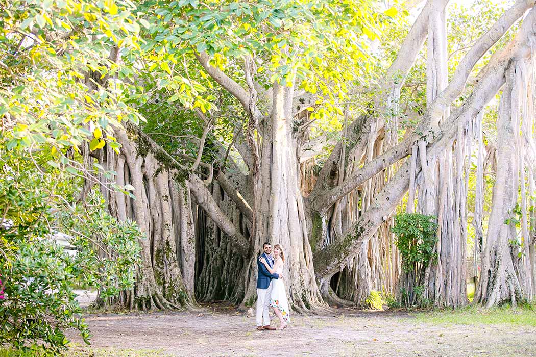 unique photograph of engaged couple standing in front of large hammock tree | park engagement photoshoot fort lauderdale
