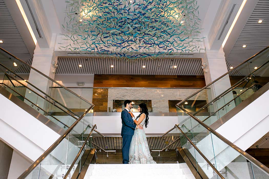 bride and groom pose on stairs of hotel