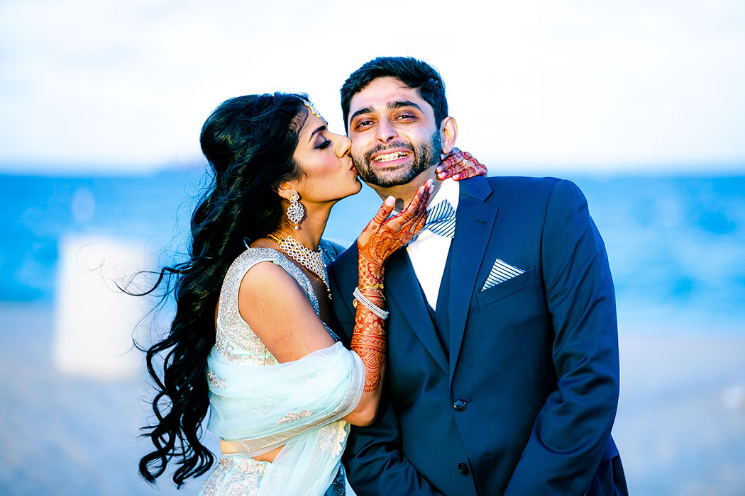 indian bride kisses groom on cheek | indian wedding on beach in fort lauderdale