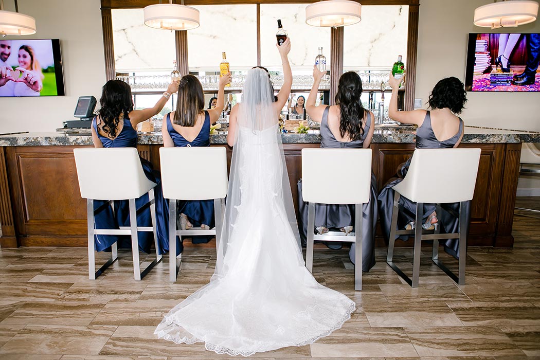 bride and her bridesmaids fun bar shot raising glasses