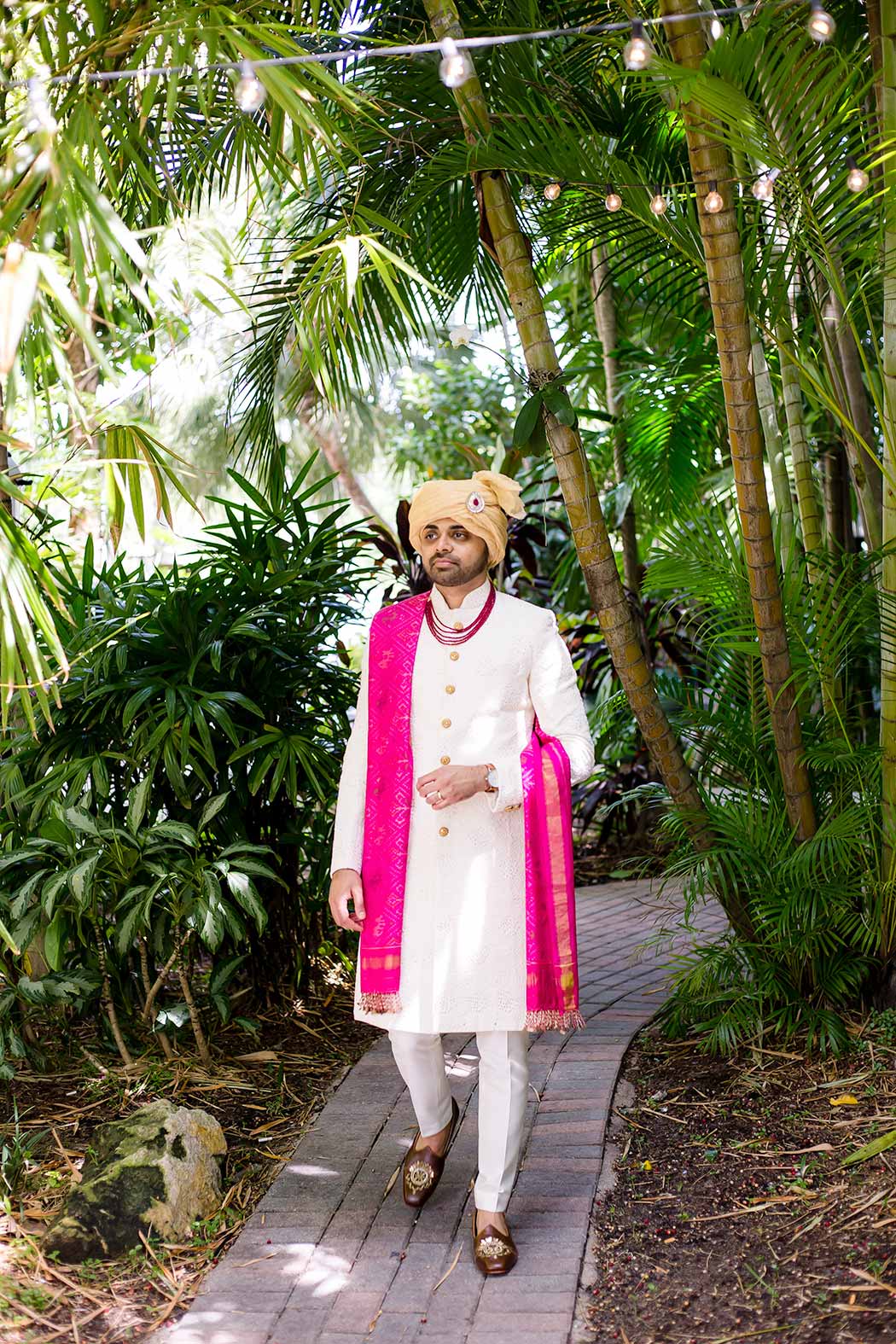 south indian groom prepares for wedding in fort lauderdale | indian groom wearing white suit with pink wrap | gold indian wedding turban | indian groom photograph