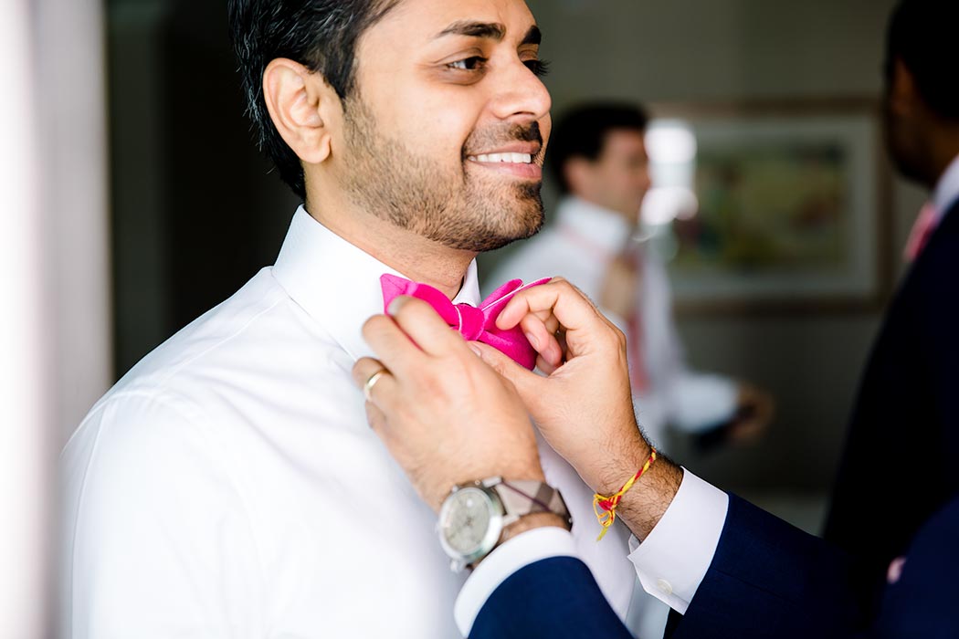 indian groom getting ready in fort lauderdale | hindu wedding fort laudedale | groom in pink bow tie | best man helping groom getting ready | pink wedding bow tie