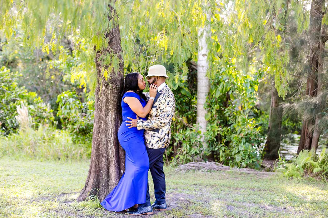 unique photograph of engaged couple standing in front of large tree | tree tops park engagement photoshoot fort lauderdale | fort lauderdale engagement photographer