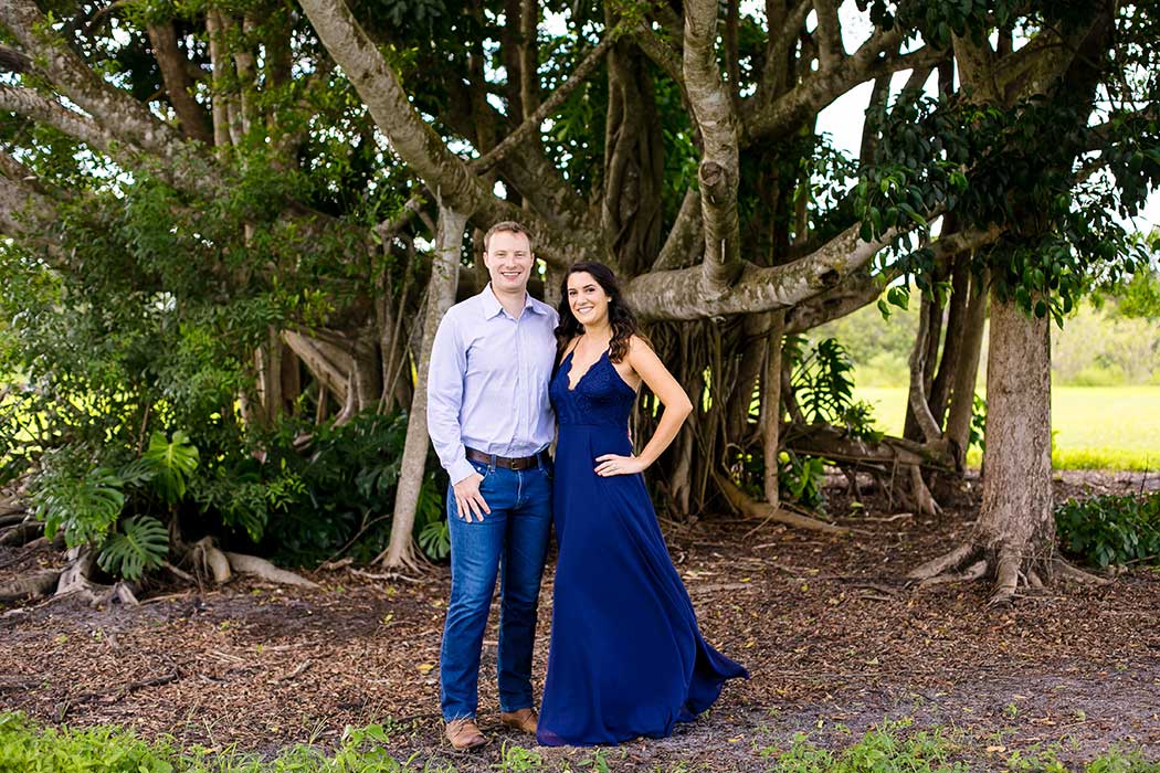 couple pose for robbins park photos | engagement photoshoot robbins preserve park in davie | formal attire for photography | floor length navy blue engagement dress