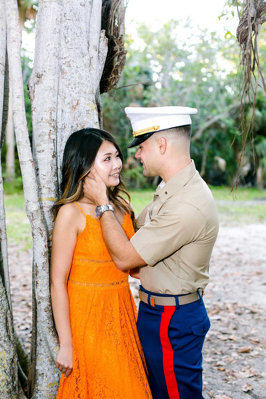 couple poses against a tree for engagement photoshoot in fort lauderdale | military uniform engagement