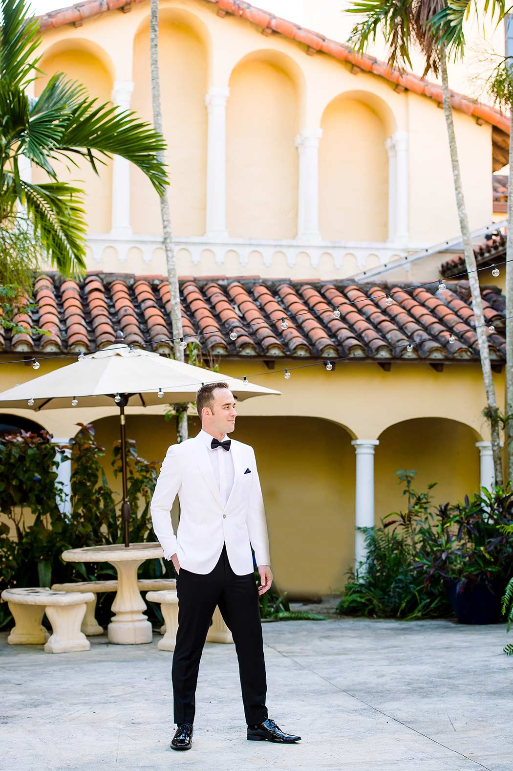 groom in white tuxedo with black bow tie and pants
