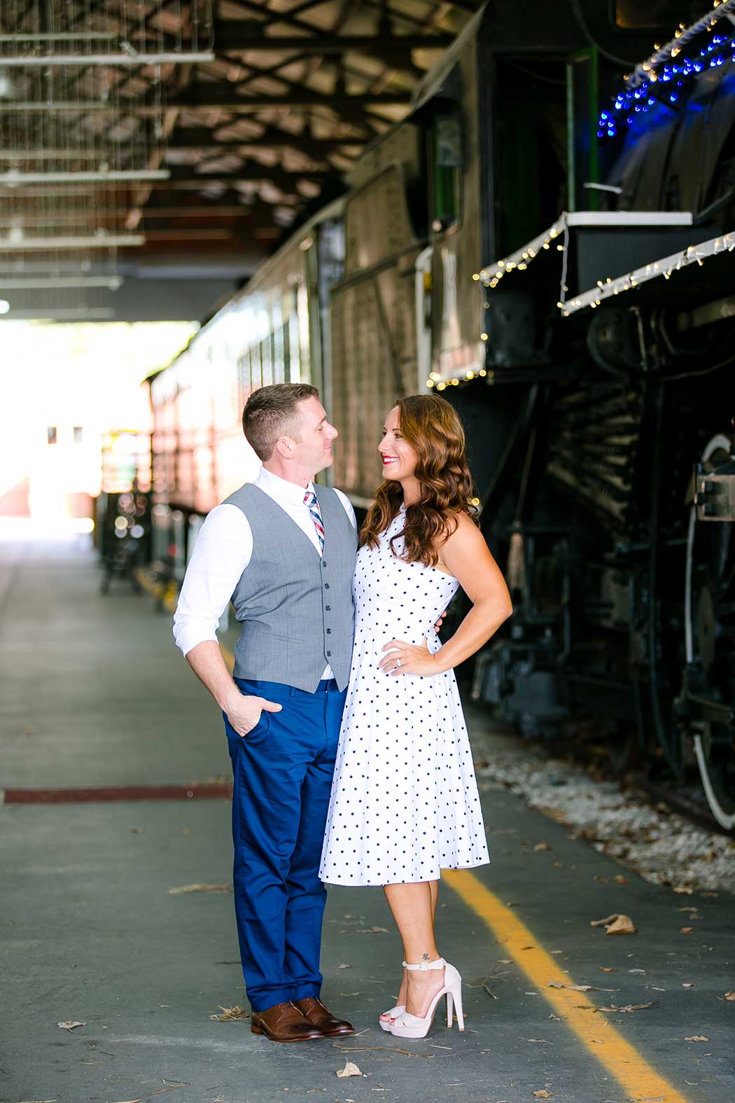 couple pose for engagement photography next to train | gold coast railroad museum photoshoot