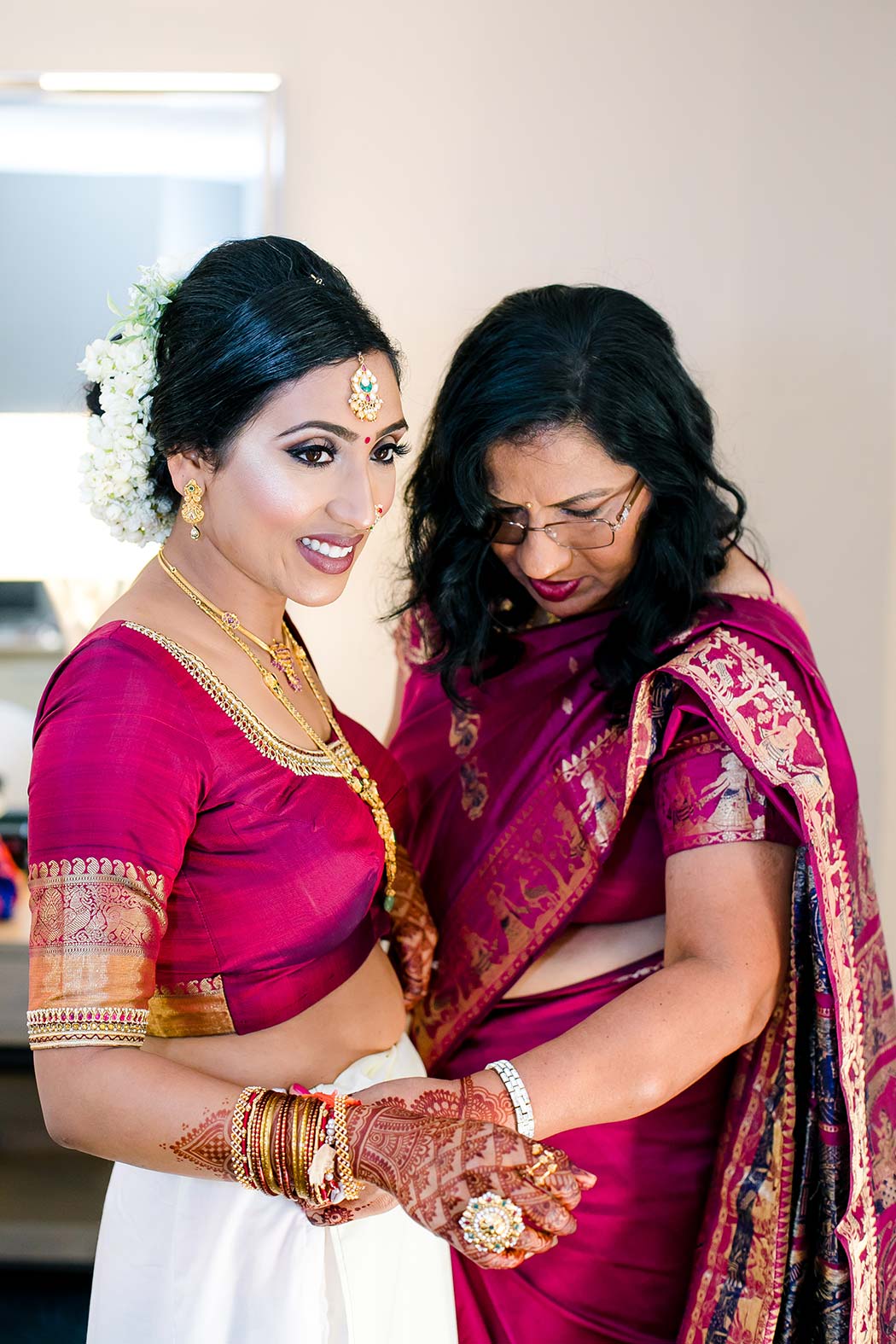indian bride putting on her gold and red sari for her south florida wedding at bahia mar
