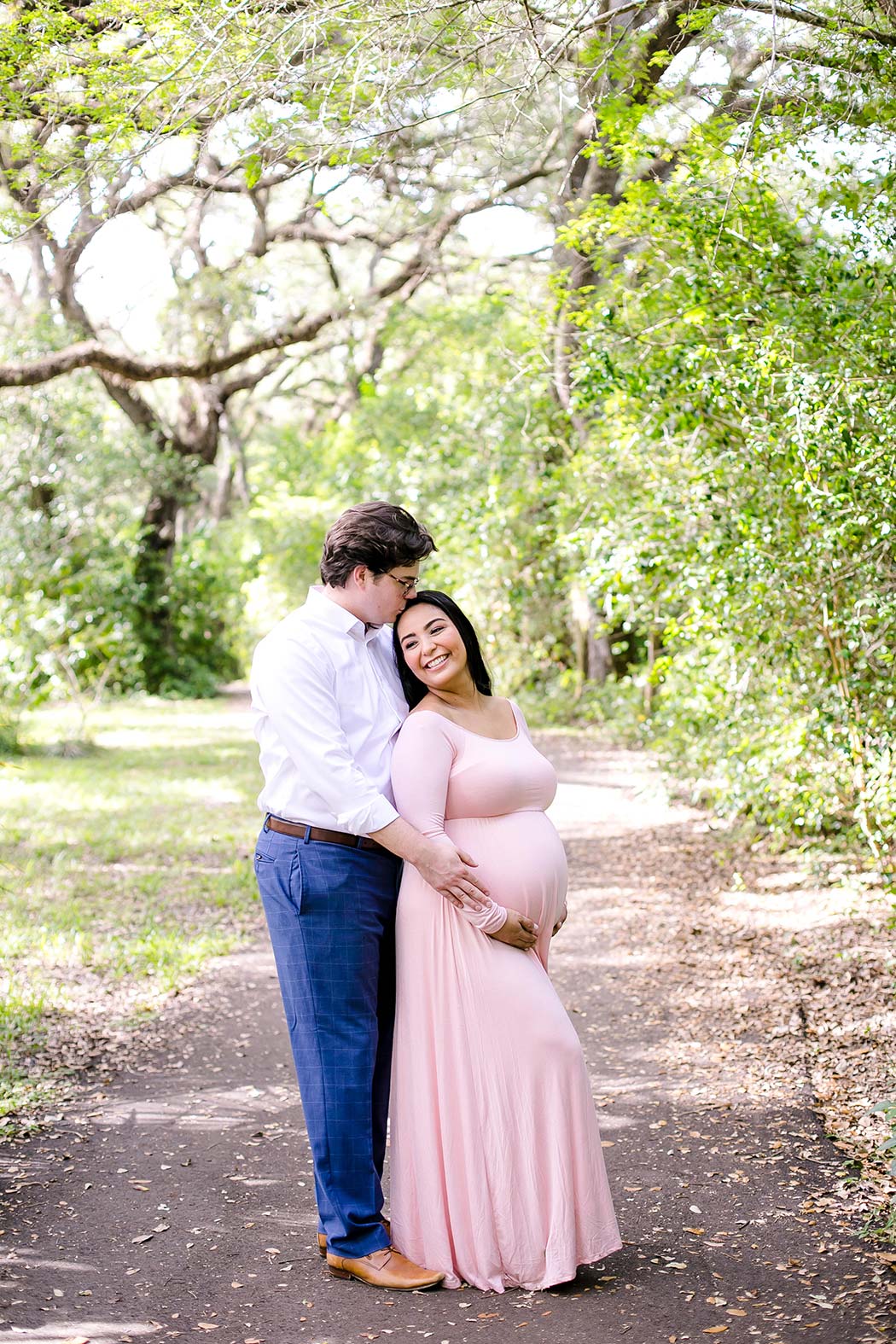 woman holds belly for maternity photography | maternity poses holding belly | pink long maternity dress | maternity session in south florida park