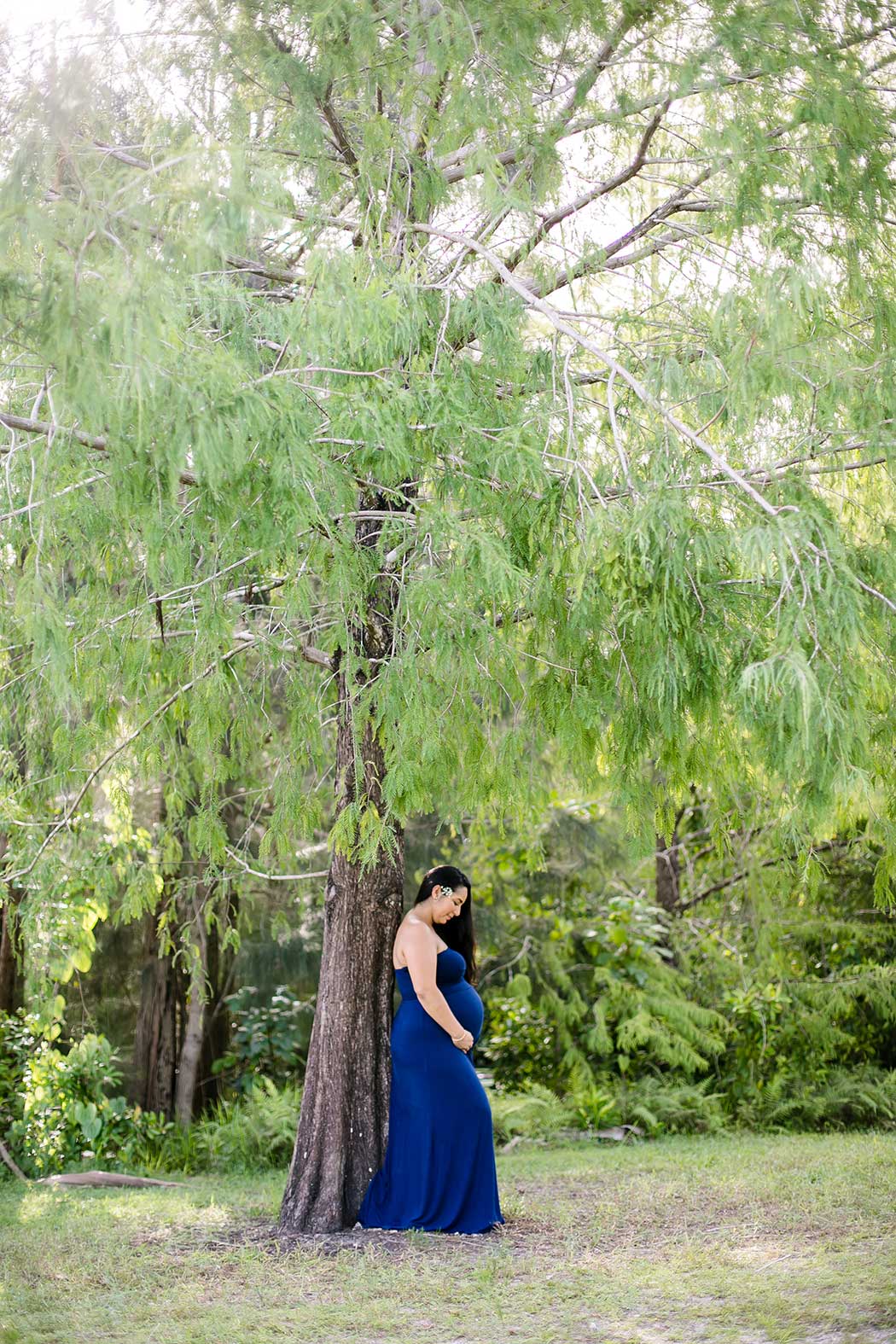 girl in navy maternity dress poses next to tree | maternity photography unique | unique maternity photography session | tree tops park maternity photoshoot | fort lauderdale maternity photographer