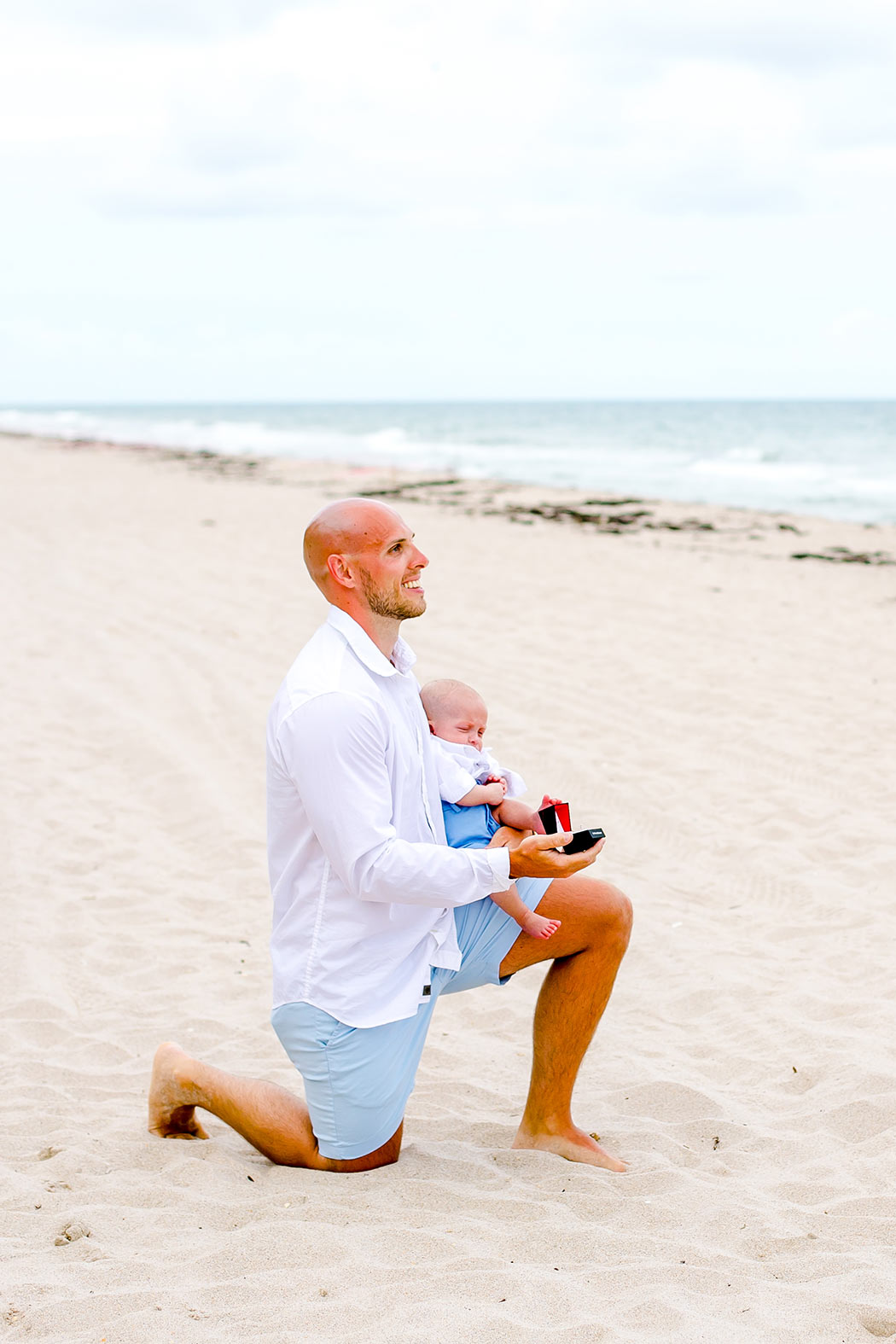 fort lauderdale beach surprise wedding proposal | guy on one knee proposes to girlfriend on fort lauderdale beach  | surprise wedding proposal with young baby