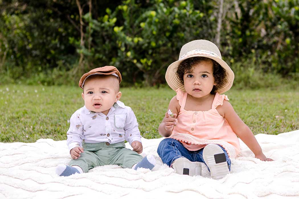 two young children sit on picnic rug in robbins park for photoshoot