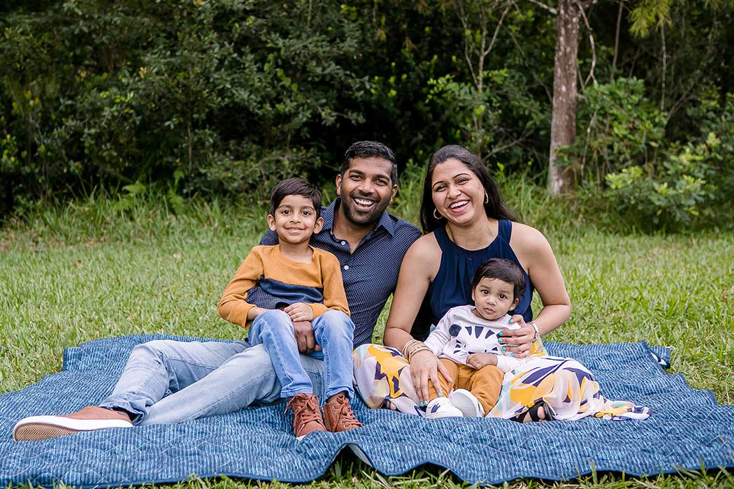 family of 4 sit on picnic rug in robbins preserve for family photoshoot