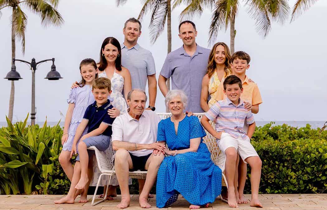 Large extended family posing together with the ocean and Fort Lauderdale Beach in the background