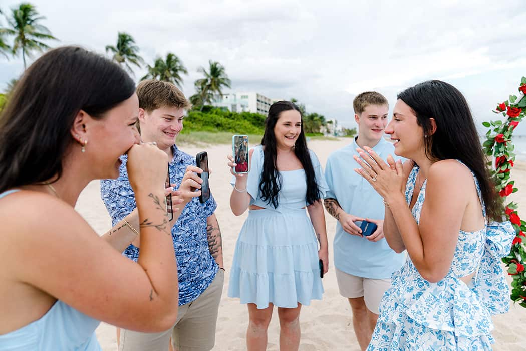 Newly engaged couple celebrating their Fort Lauderdale Beach proposal with family on a video call